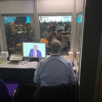 Rear view of interpreter sitting in a soundproof booth providing simultaneous interpretation