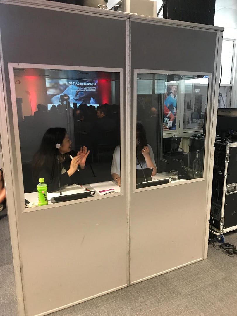 Interpreters in soundproof booth, interpreting for a business meeting